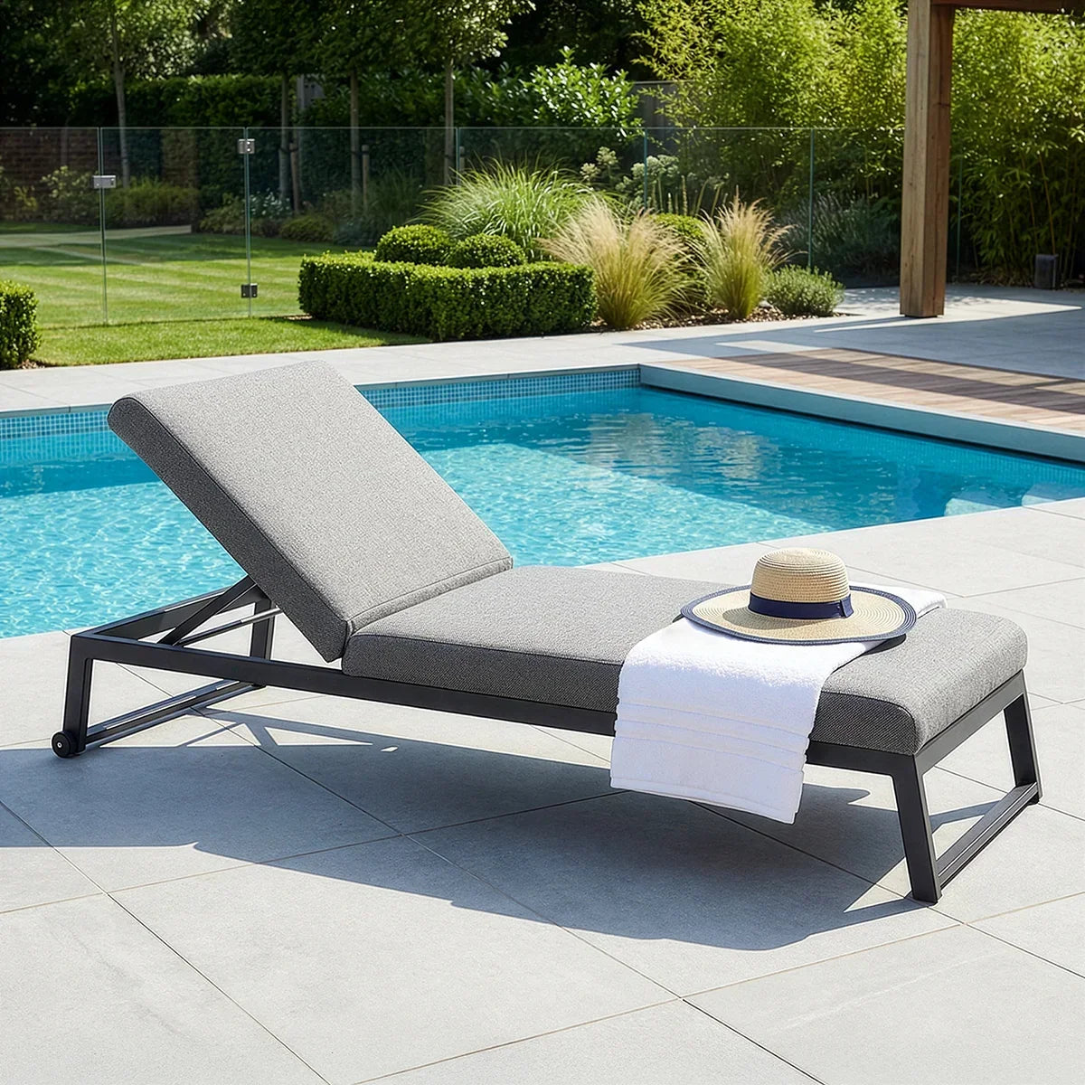 Grey aluminum sun lounger with adjustable backrest beside a swimming pool