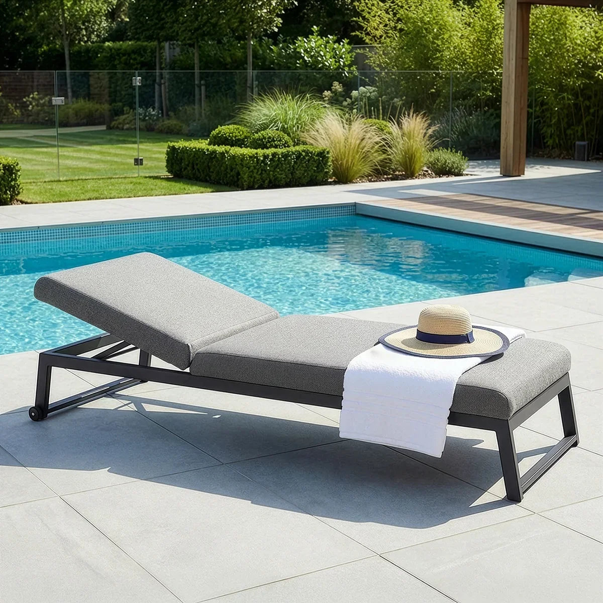Grey aluminium sun lounger with adjustable backrest by pool, towel and hat on seat