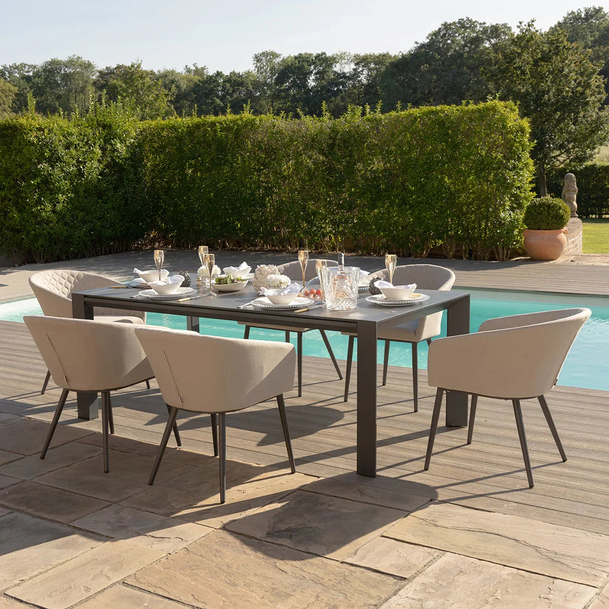 Outdoor dining set with beige chairs and black table beside a pool, table set for six