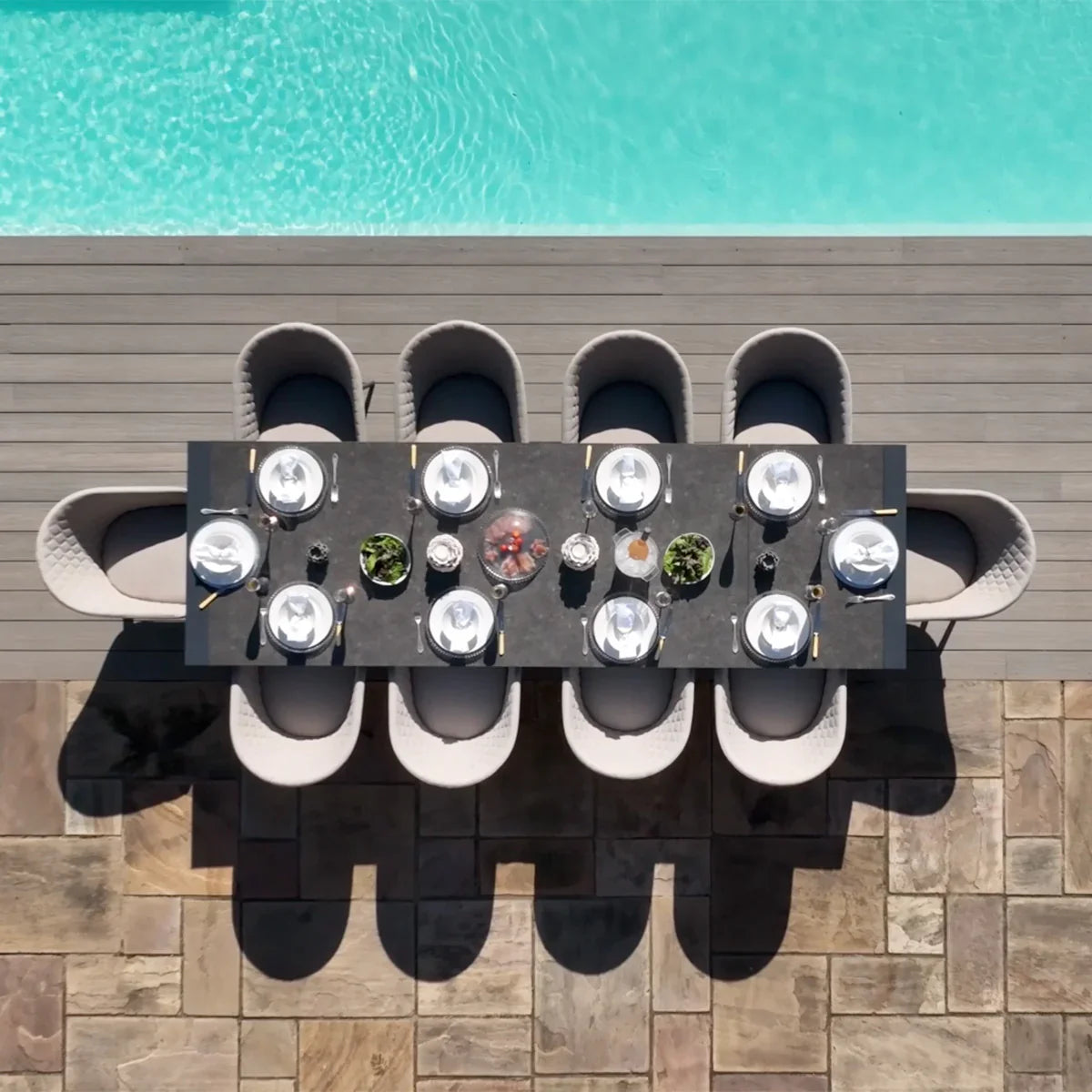 Outdoor dining set with eight grey chairs and a rectangular table beside a swimming pool