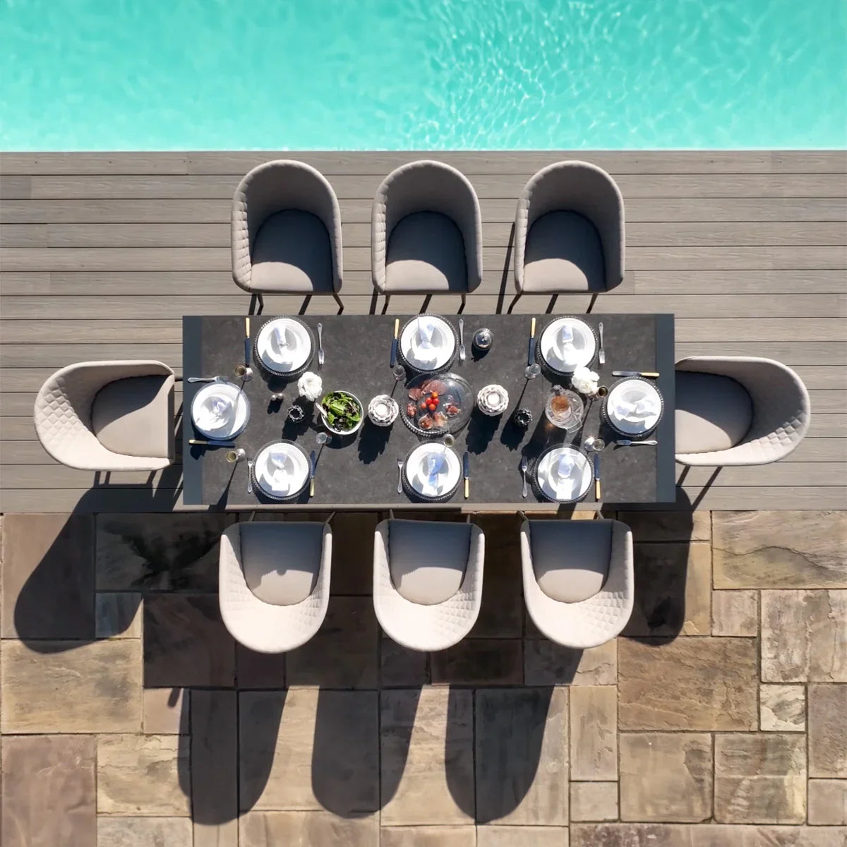 Outdoor dining set with eight cushioned chairs and rectangular table by a swimming pool