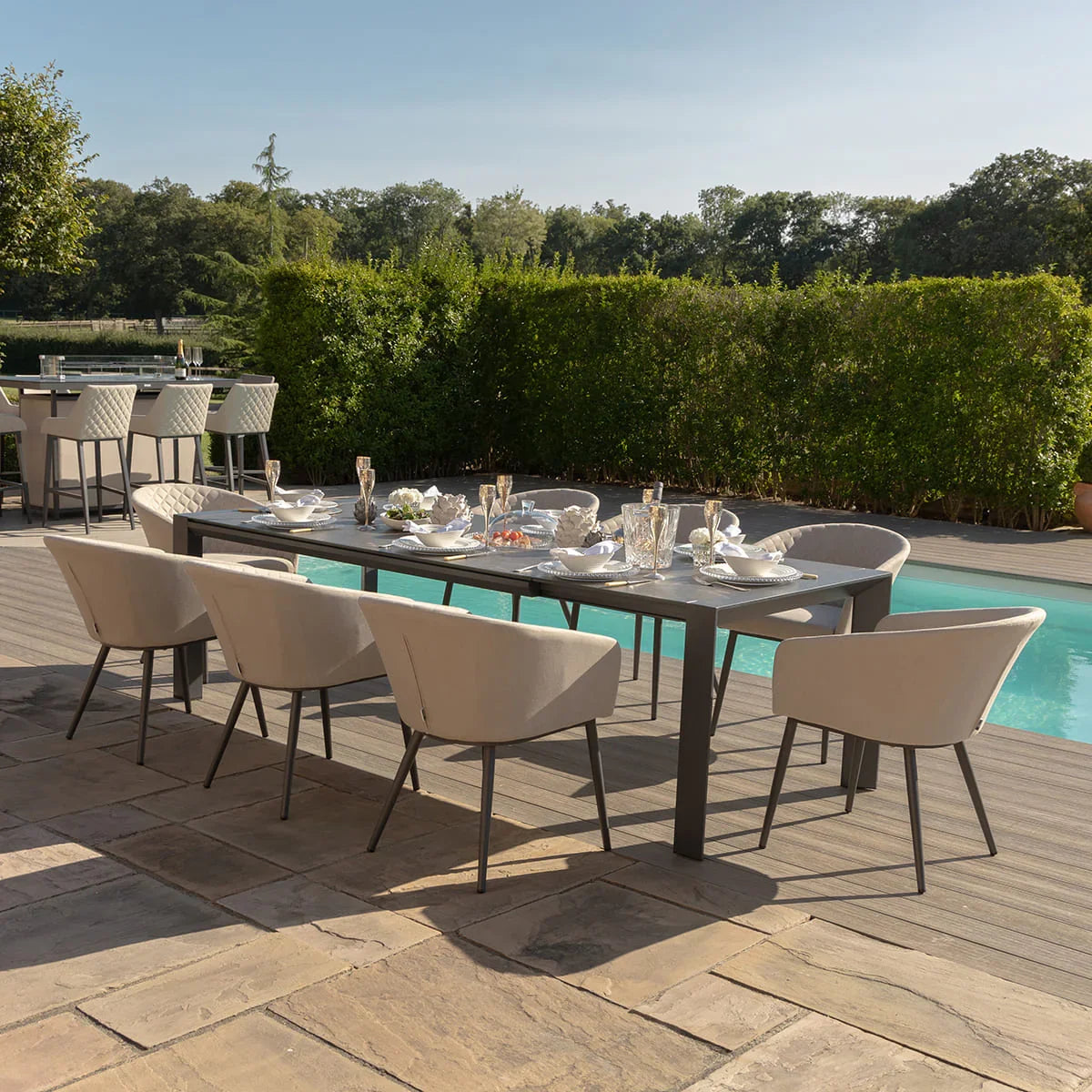 Outdoor dining set with beige cushioned chairs and rectangular table next to swimming pool