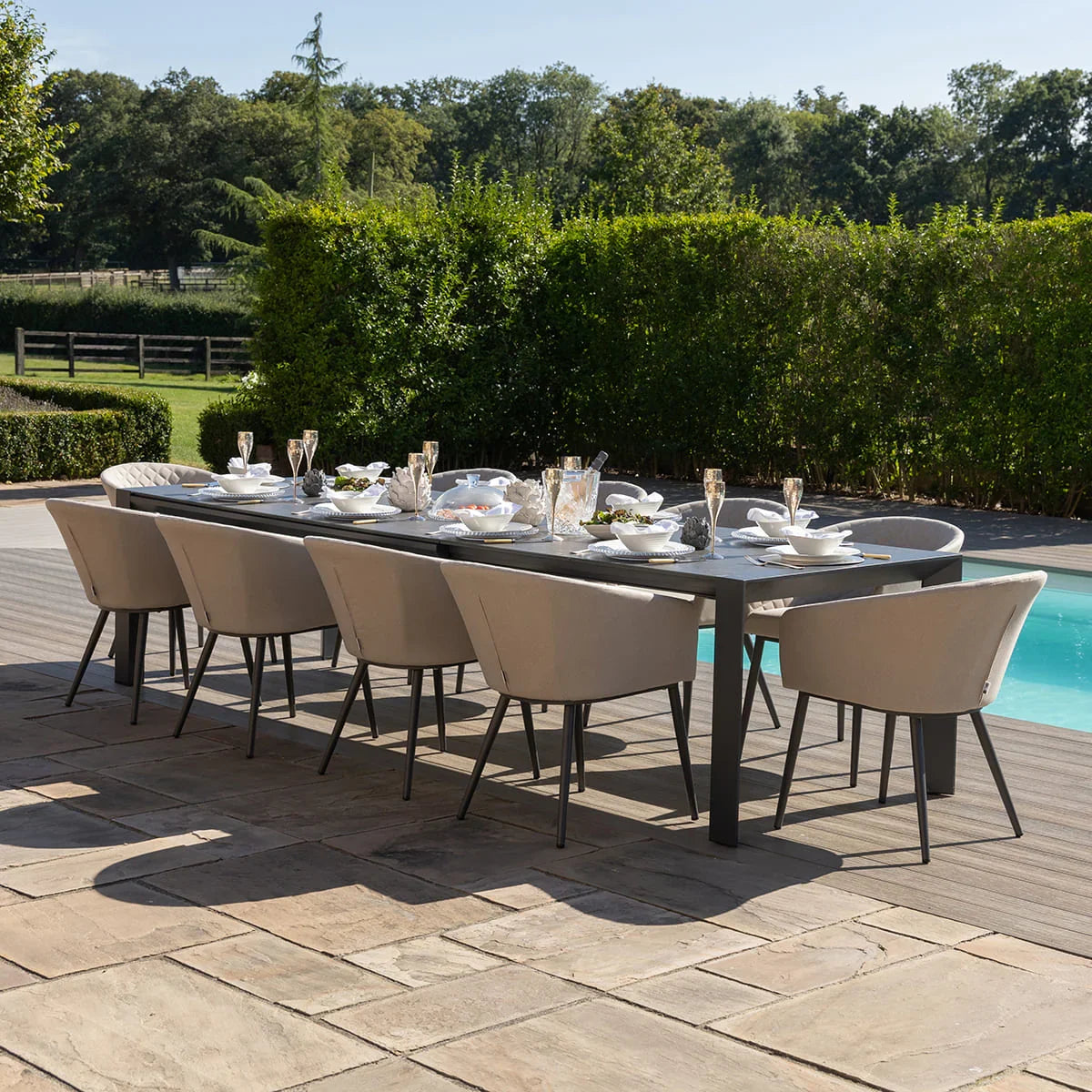 Modern outdoor dining set with eight beige armchairs and long rectangular table by pool