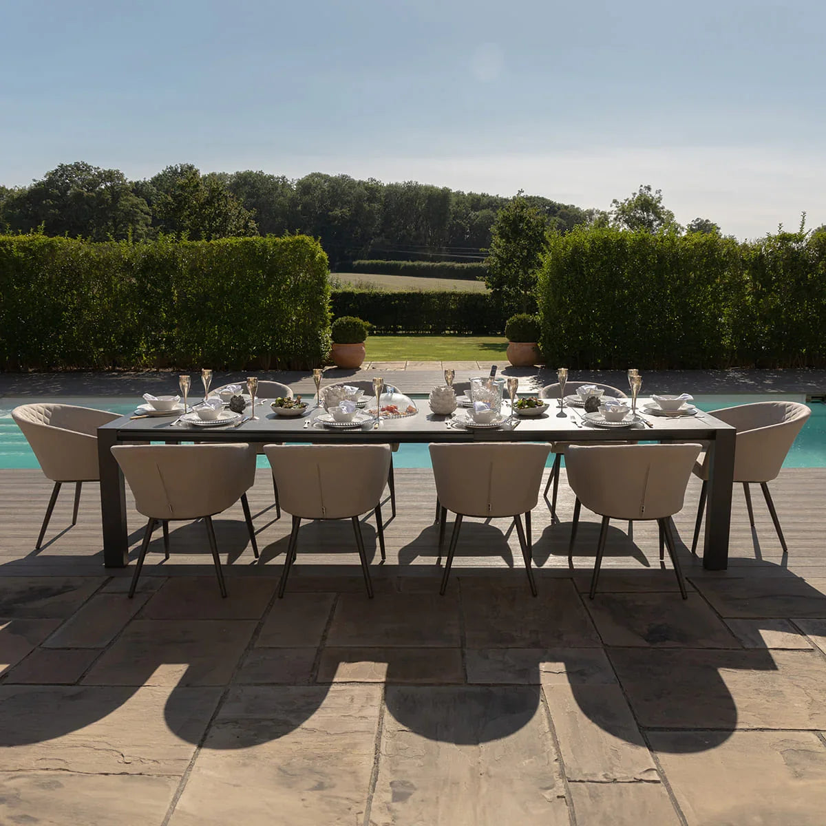 Outdoor dining set with eight cushioned chairs and rectangular table by pool on patio