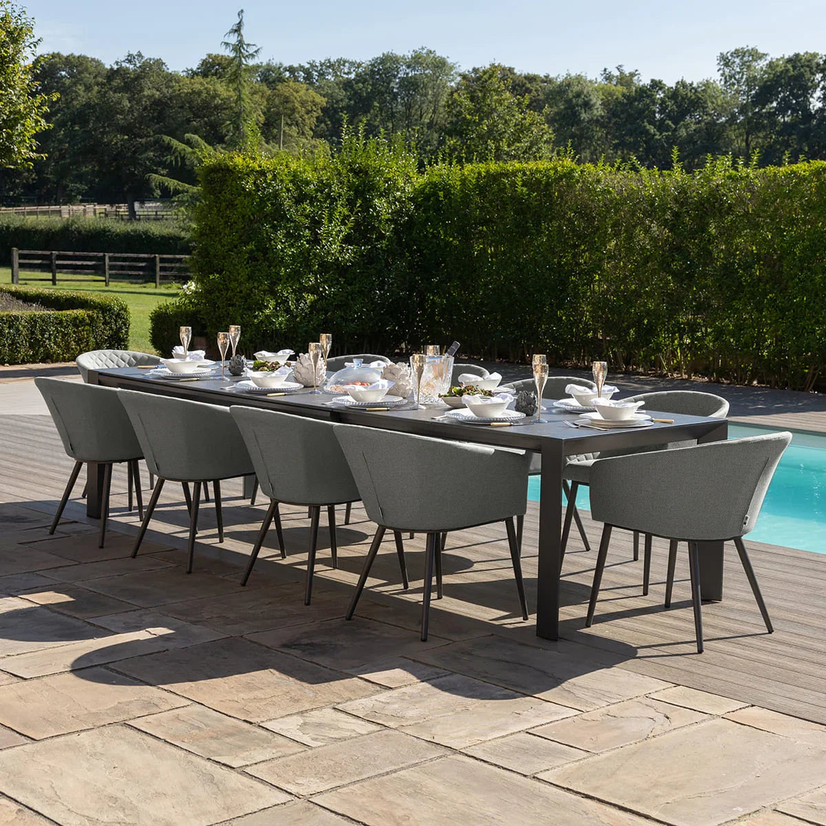 Modern outdoor dining set with grey chairs and rectangular table by a pool on a patio