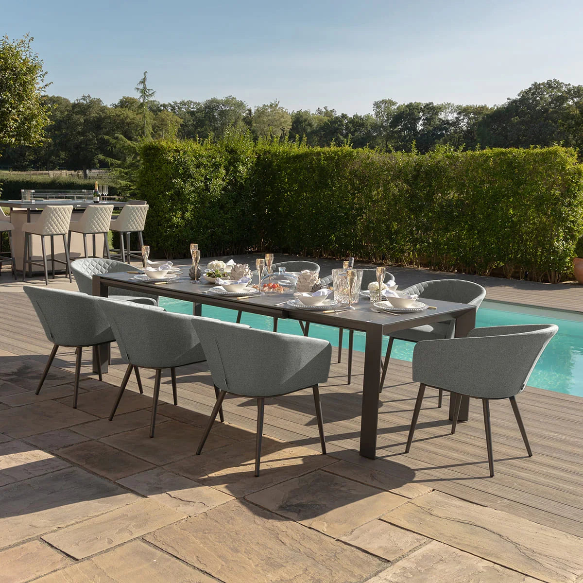 Grey outdoor dining set with six armchairs around rectangular table beside pool