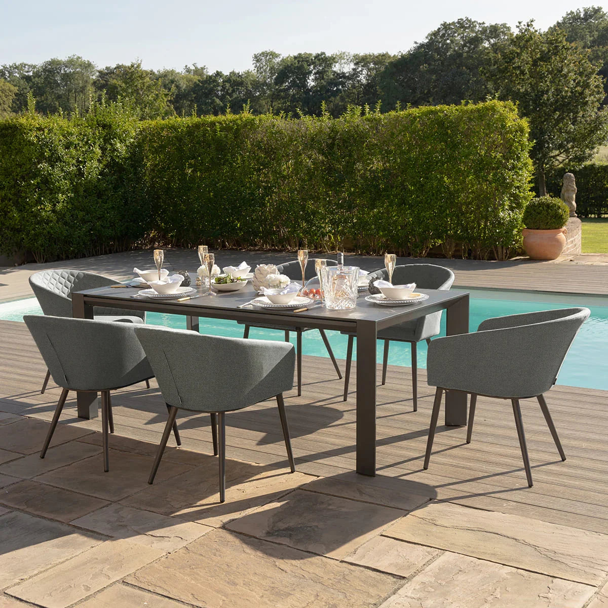 Grey outdoor dining set with six chairs and rectangular table beside swimming pool