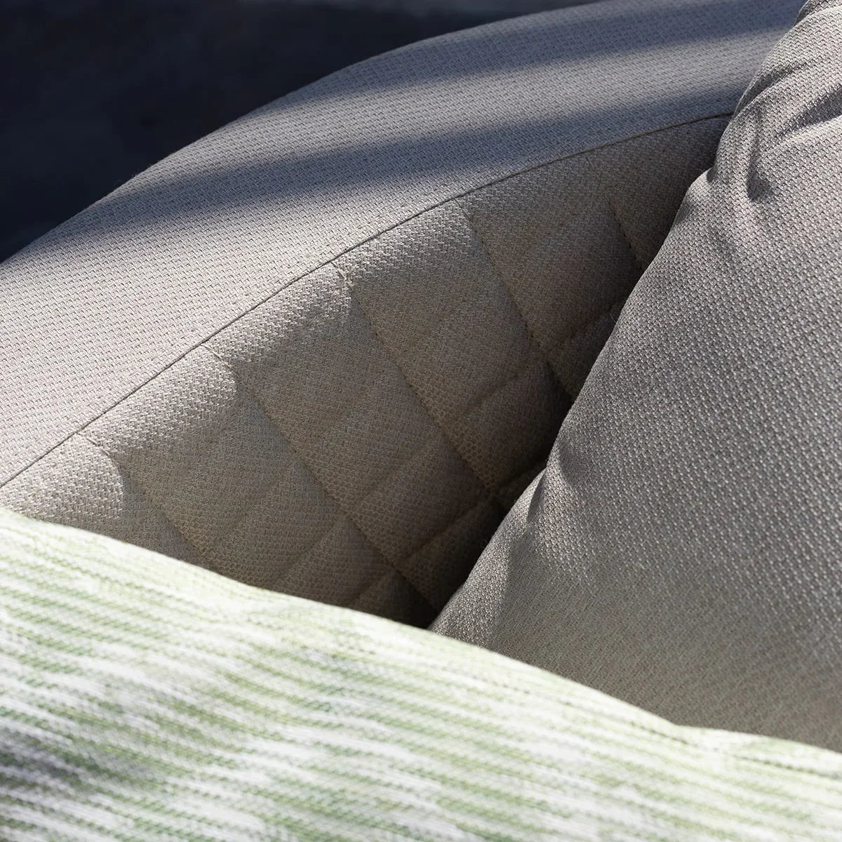 Beige outdoor sofa backrest with quilted detail and textured cushion close-up