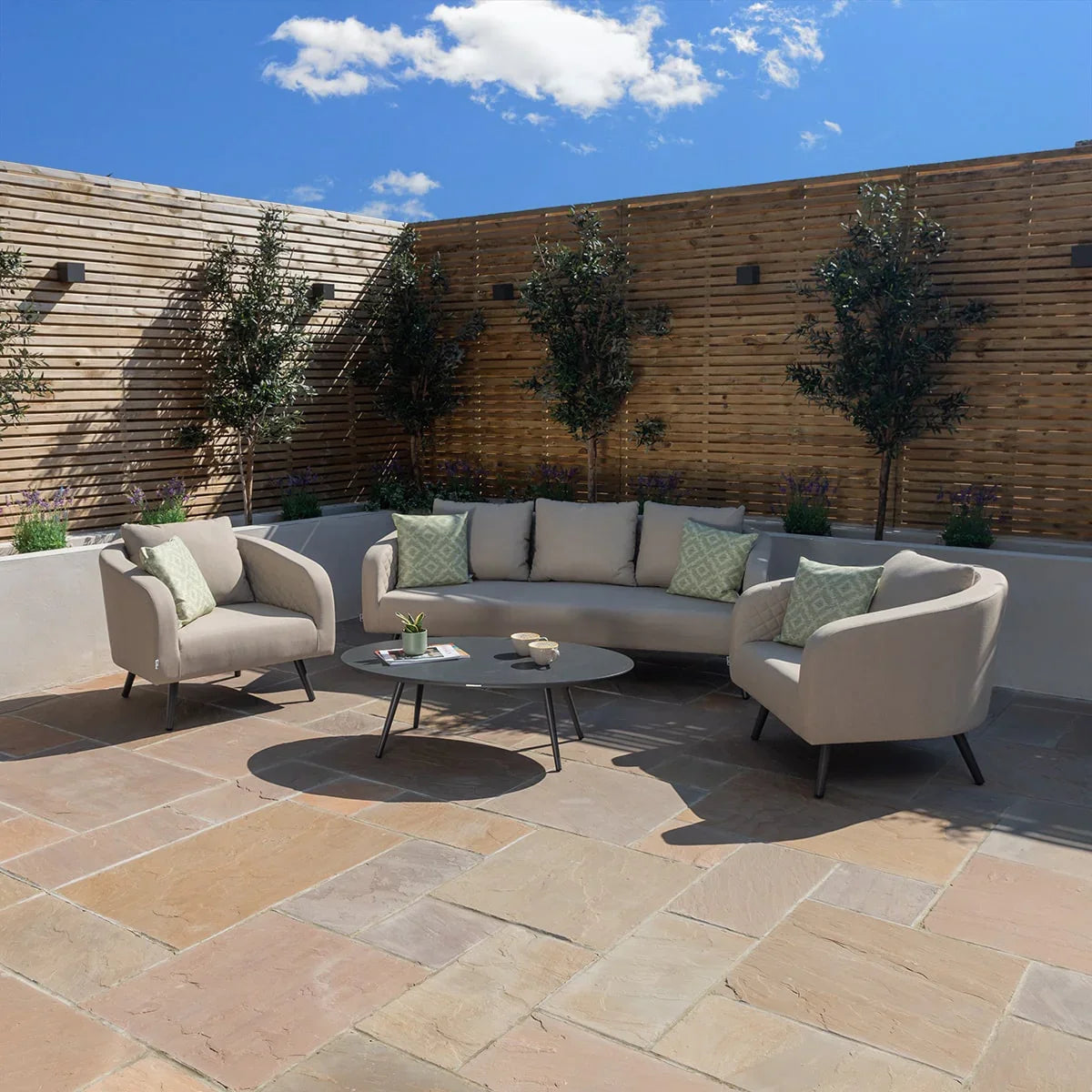 Beige outdoor sofa set with armchairs and cushions around a round coffee table on patio