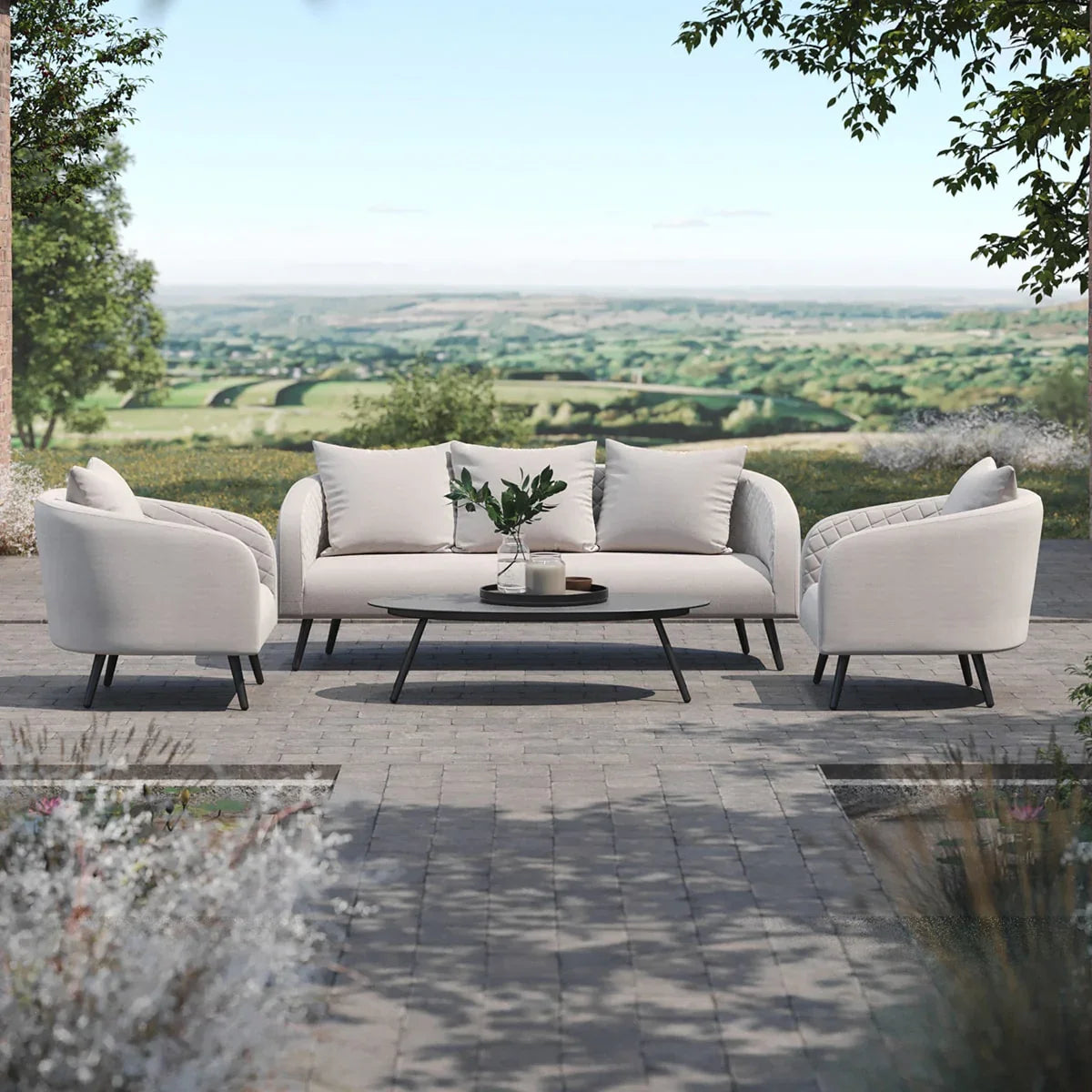 Outdoor garden sofa set with light beige cushions and matching armchairs on stone patio