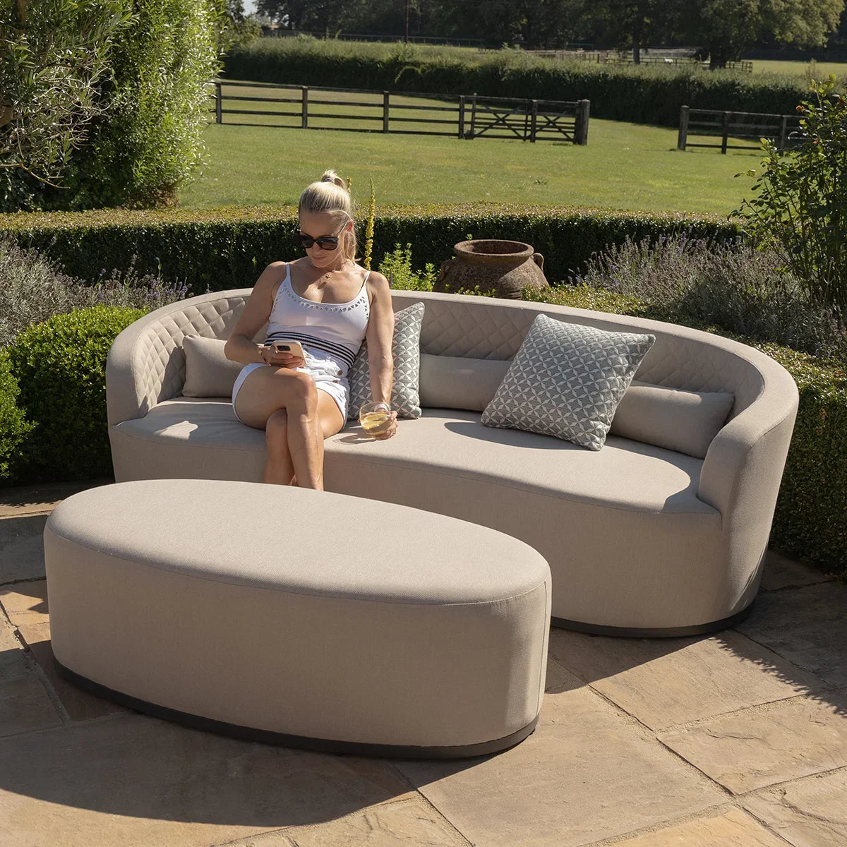 Curved beige outdoor sofa set with matching ottoman, patio setting, geometric cushions