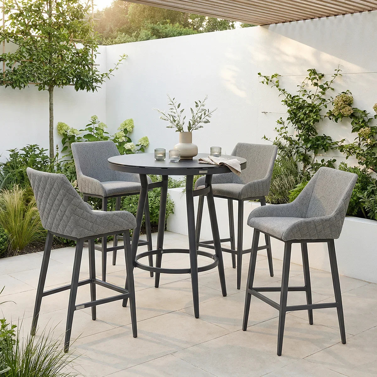 Grey bar table set with four upholstered stools in modern outdoor patio setting