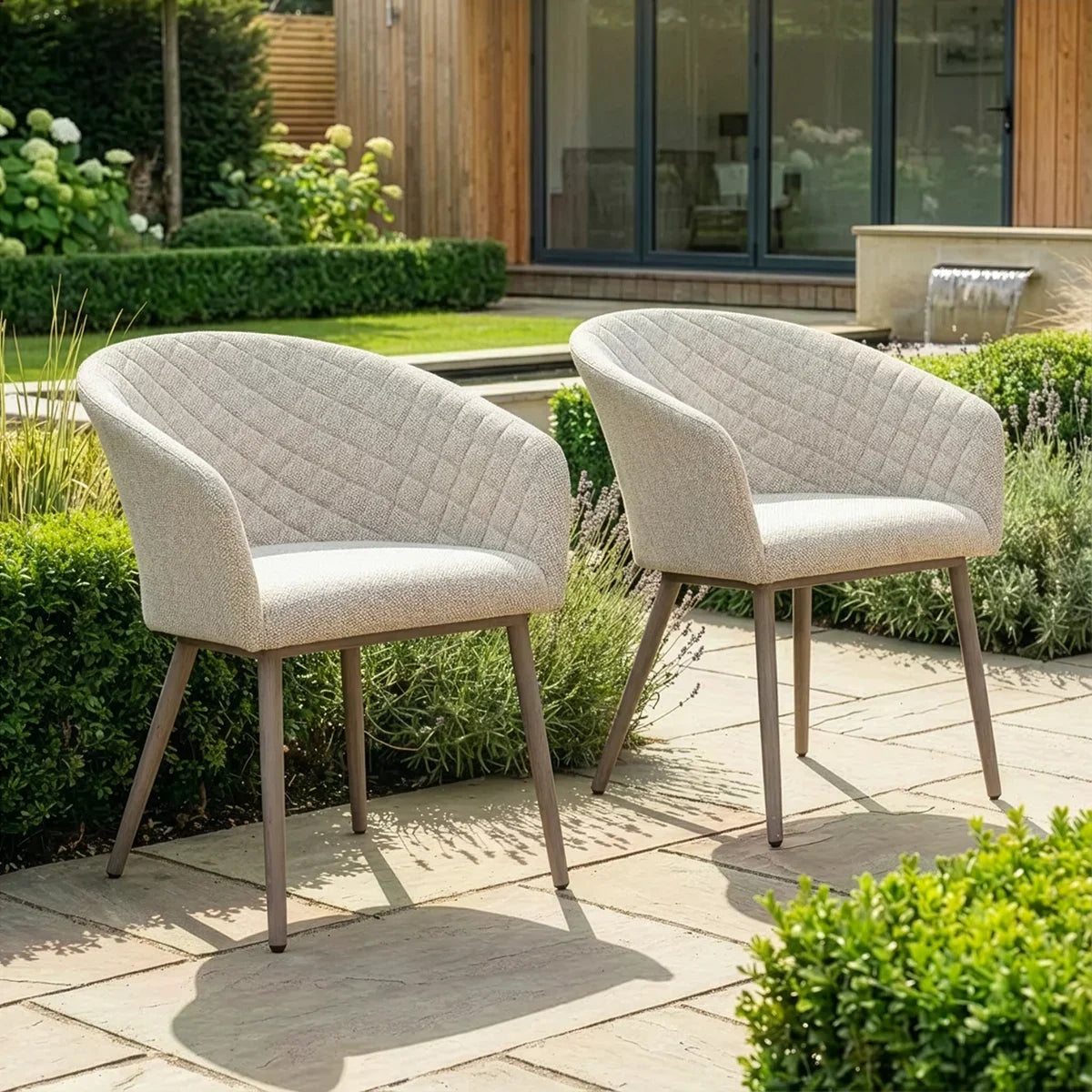 Pair of outdoor dining chairs with light upholstery and quilted backs on patio