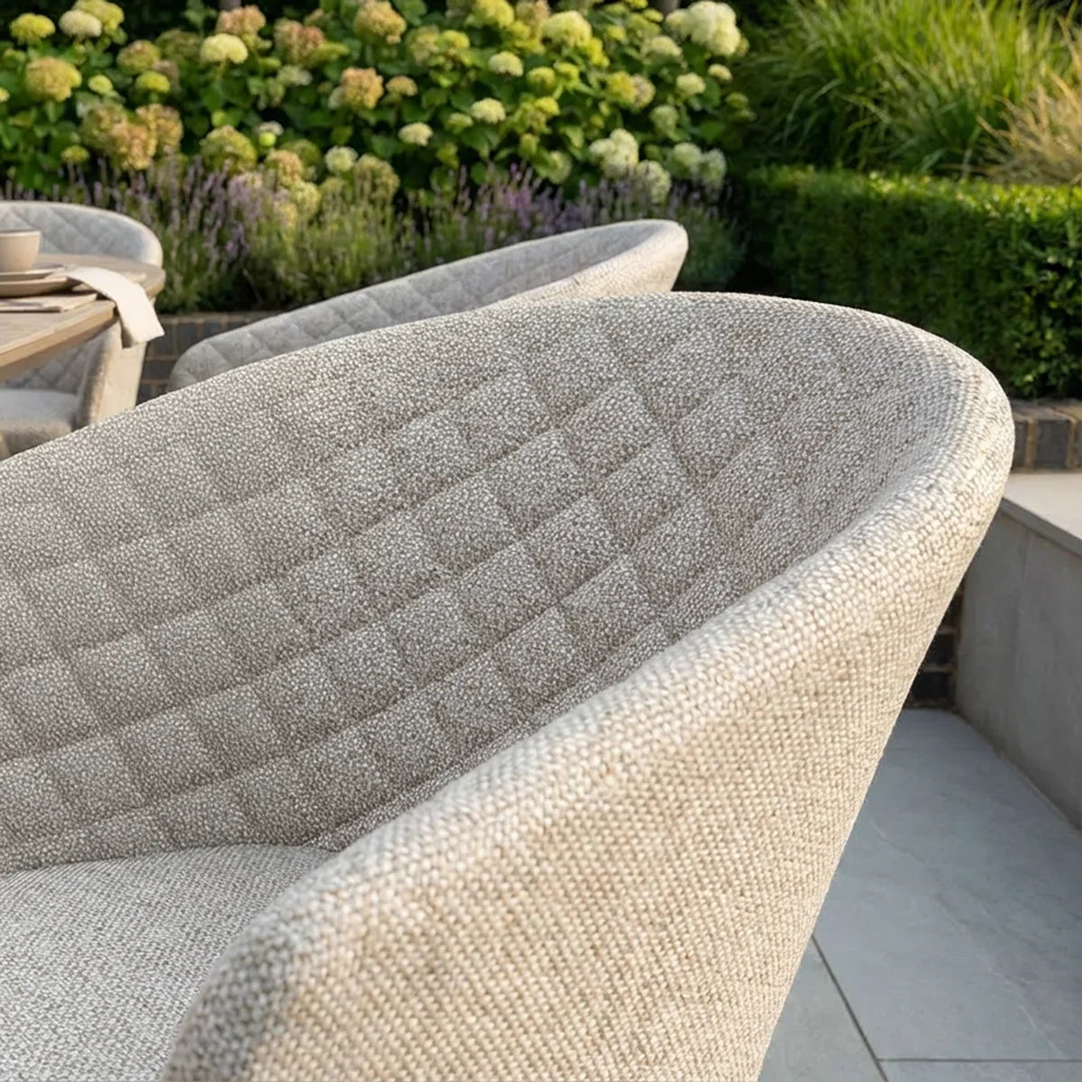 Close-up of beige outdoor dining chair with quilted backrest on patio