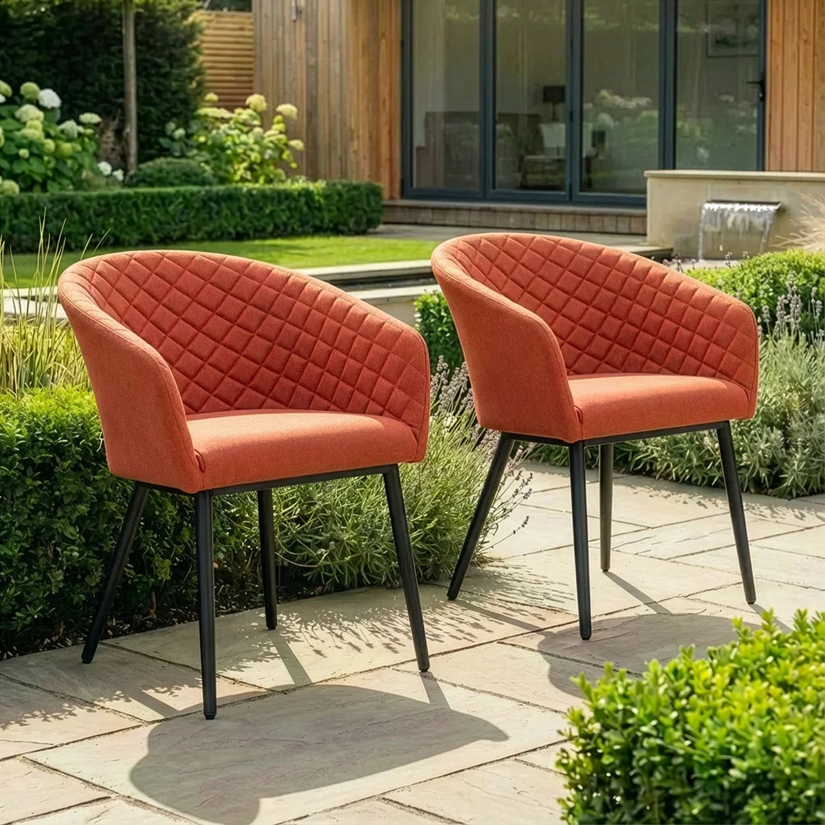 Pair of orange fabric garden armchairs with quilted backs on patio