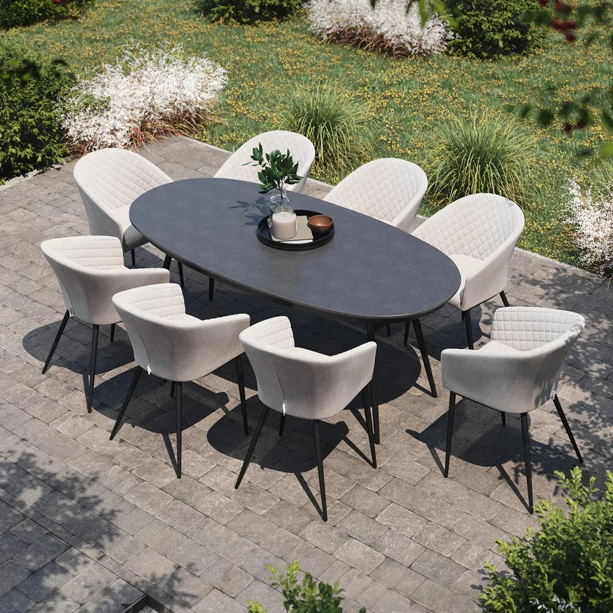 Grey oval outdoor dining table set with eight cushioned chairs on patio