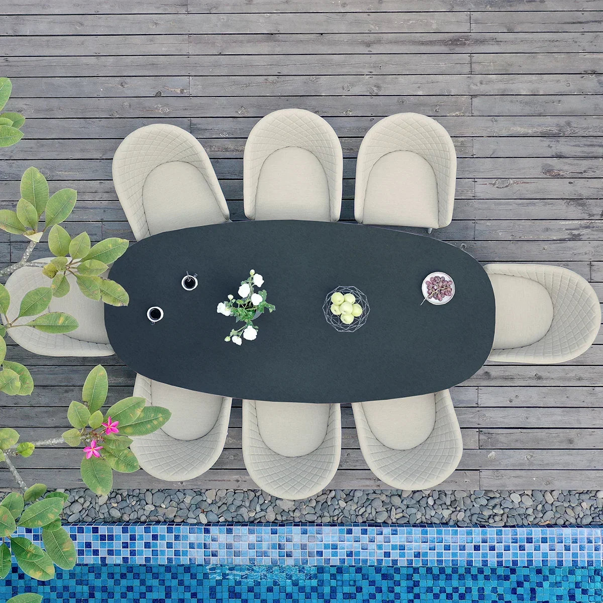 Outdoor 8 seater dining set with oval table and beige chairs on wooden decking by a pool