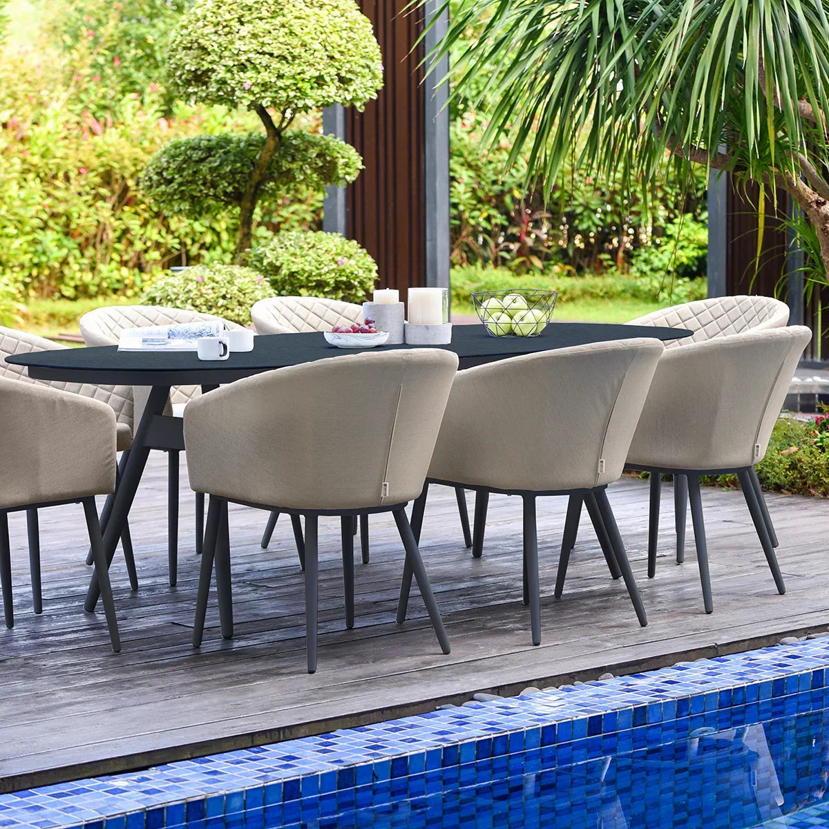Outdoor dining set with eight beige cushioned chairs and black table beside swimming pool