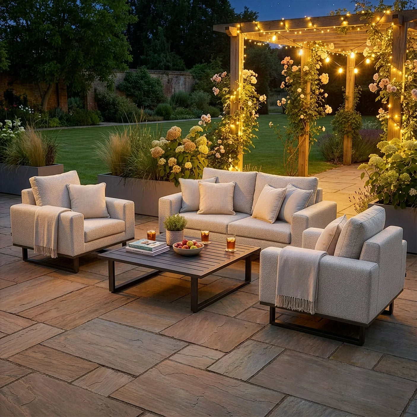 Modern outdoor sofa set with armchairs and coffee table on patio, pergola with garden lights