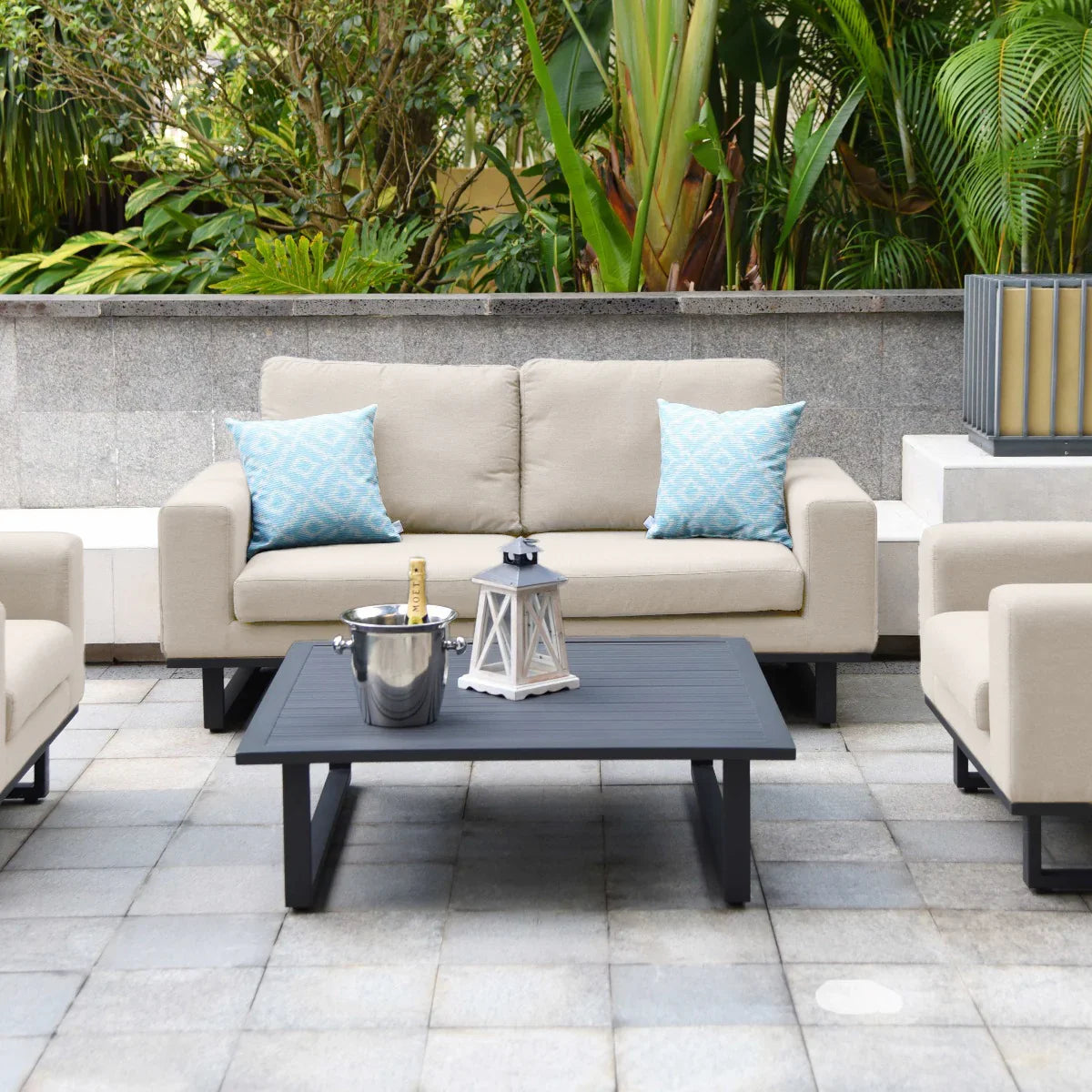 Beige outdoor sofa set with blue cushions and black coffee table on a tiled patio