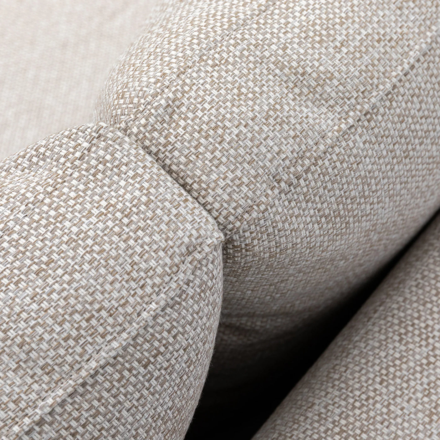 Close-up of beige fabric sofa armrest with textured upholstery and visible stitching