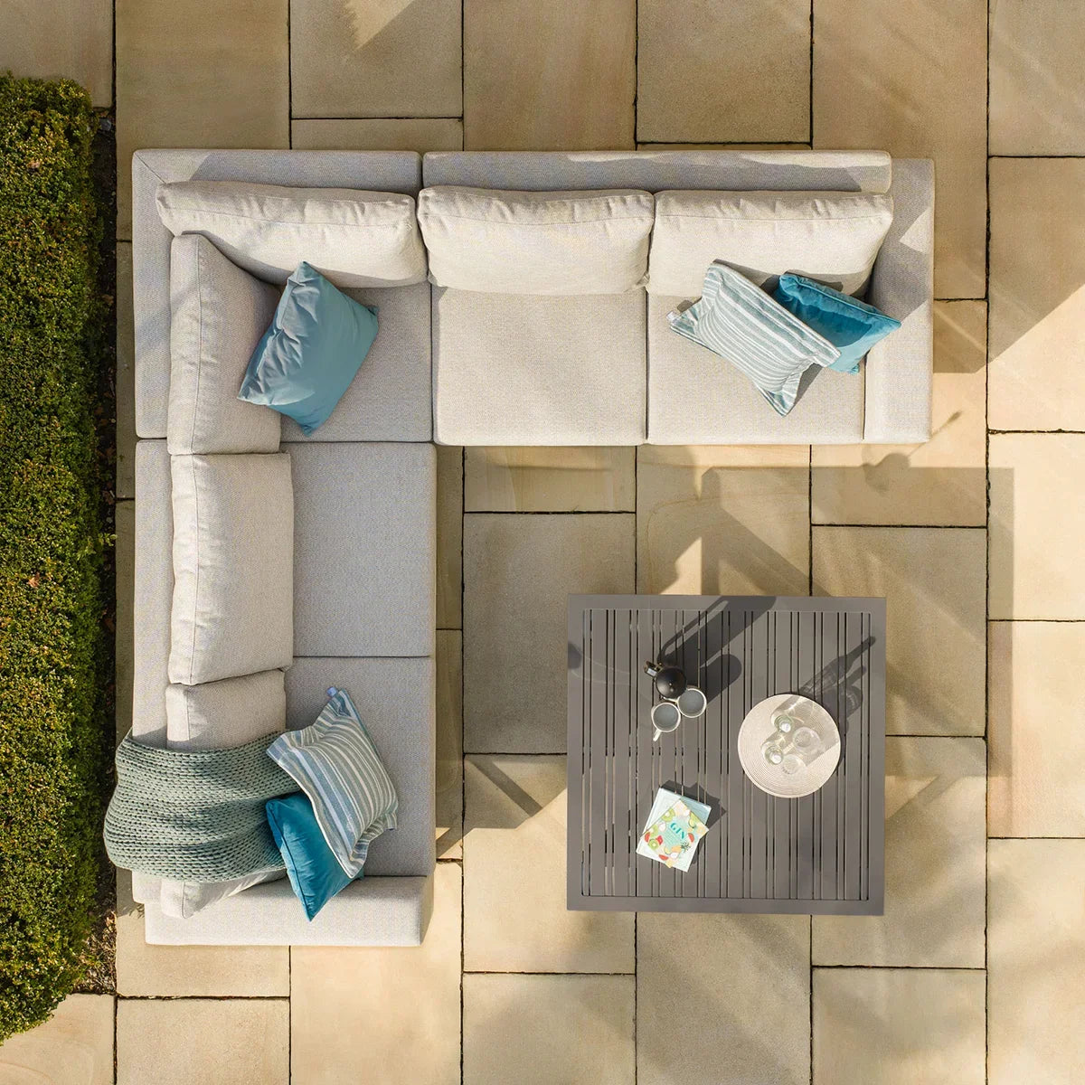 Corner outdoor sofa set with grey cushions and metal coffee table on stone patio