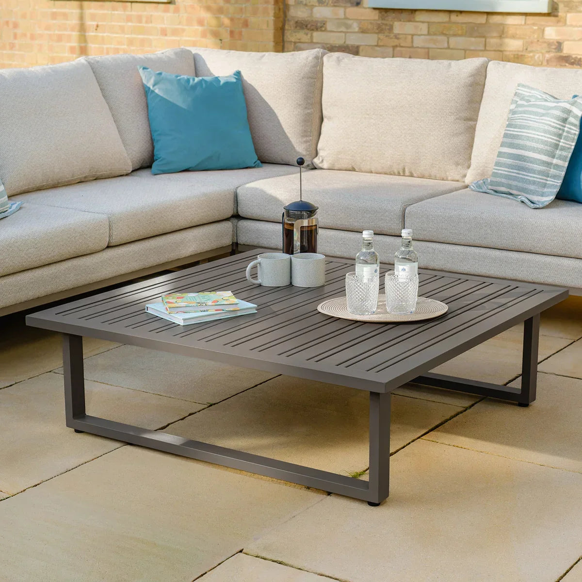 Outdoor corner sofa set with beige cushions and metal coffee table on patio
