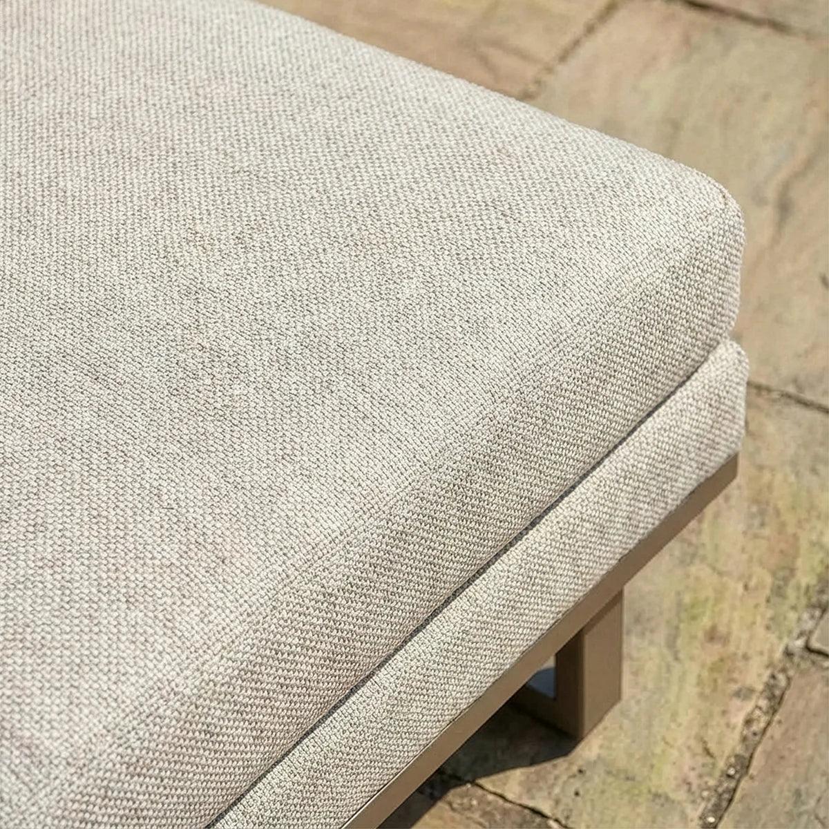 Close-up of beige outdoor furniture cushion with textured fabric on stone patio