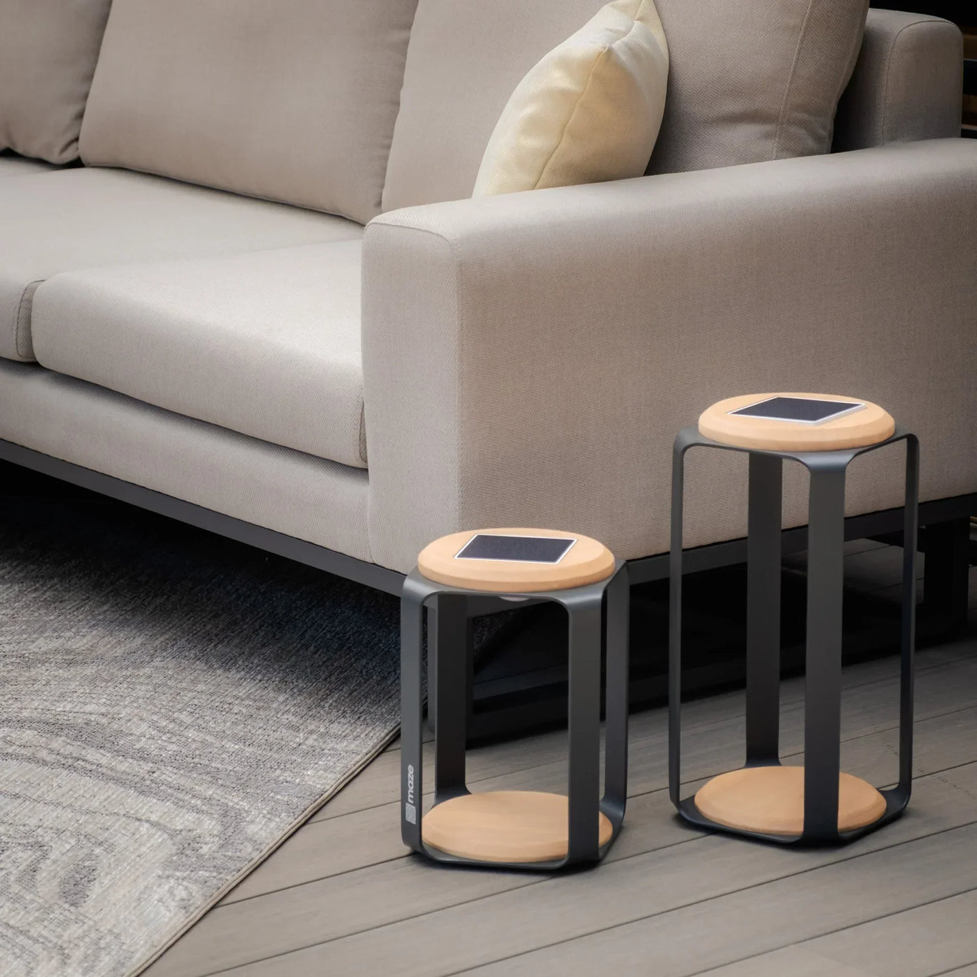 Beige fabric sofa with light wood and black metal side tables on patio decking