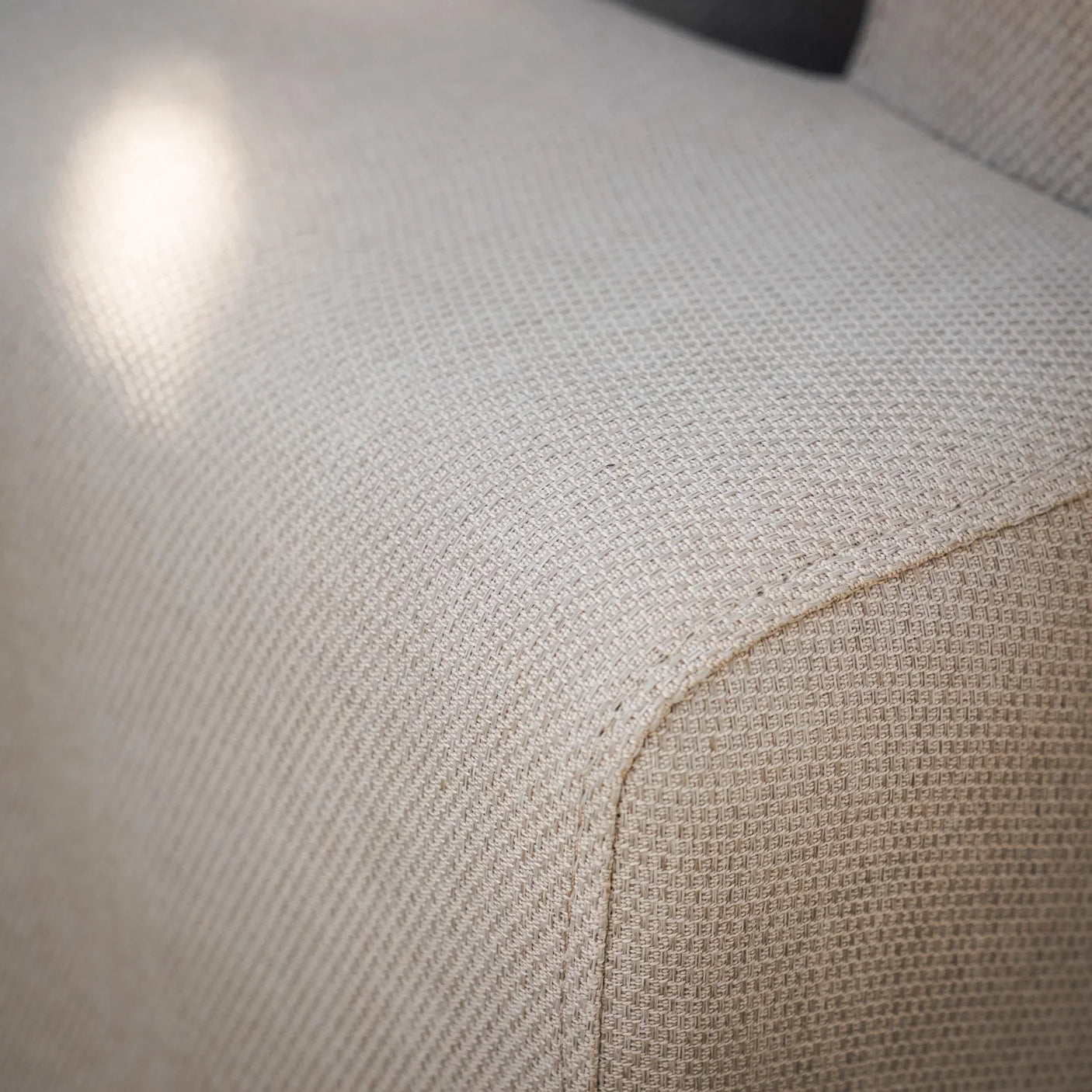 Close-up of beige fabric sofa armrest showing textured upholstery detail