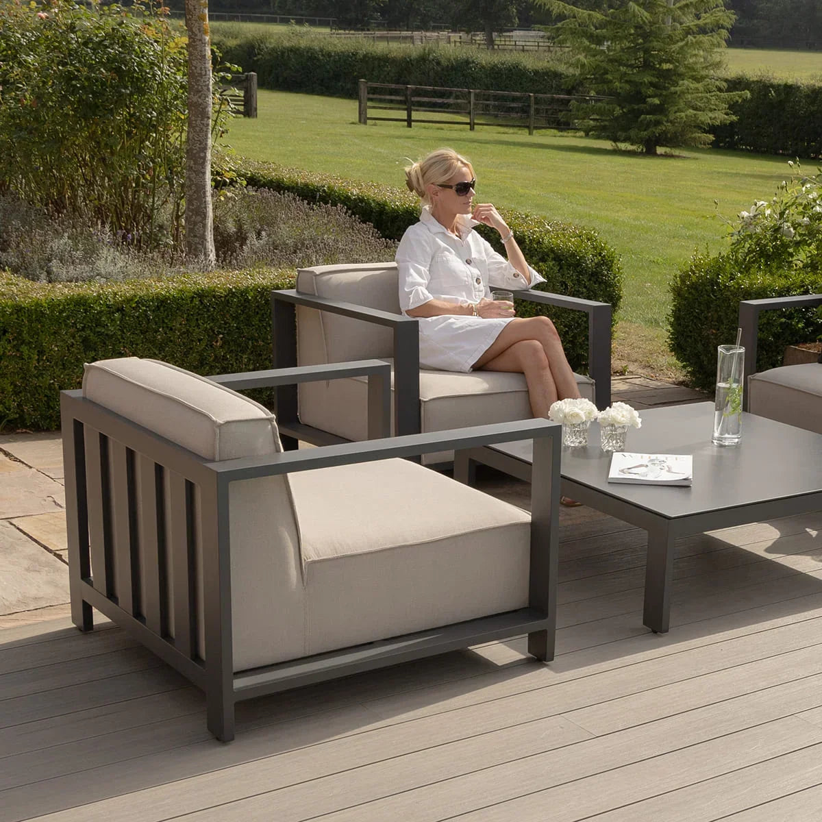 Grey outdoor lounge chair set with beige cushions and matching coffee table on patio decking