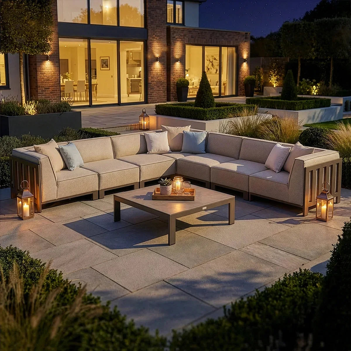 Beige outdoor corner sofa set with cushions and lanterns on a modern patio at night