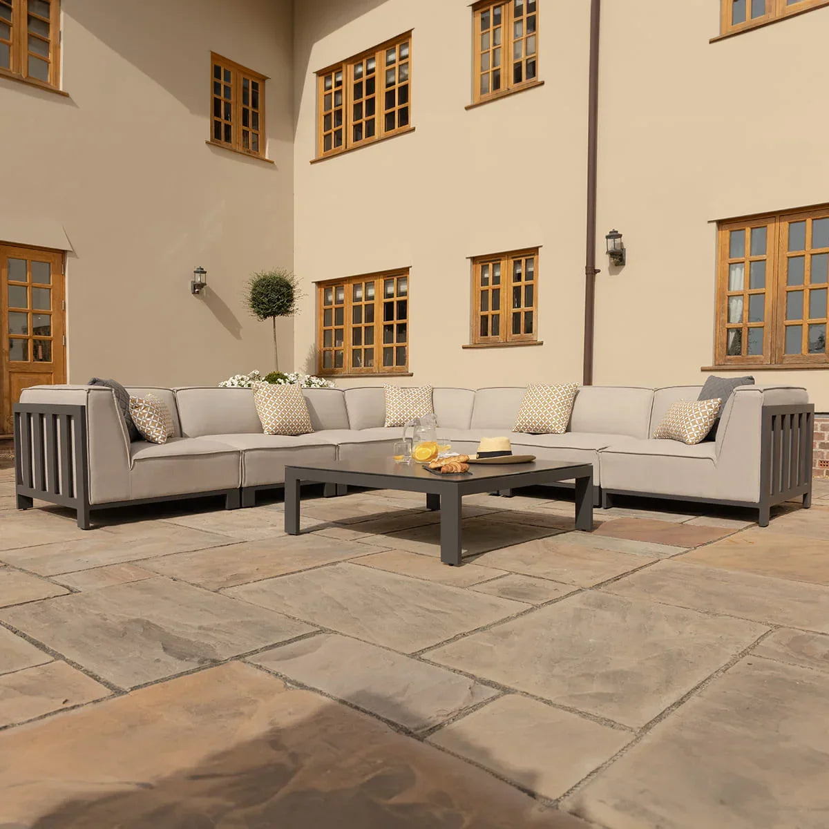 Grey outdoor corner sofa set with cushions and coffee table on patio
