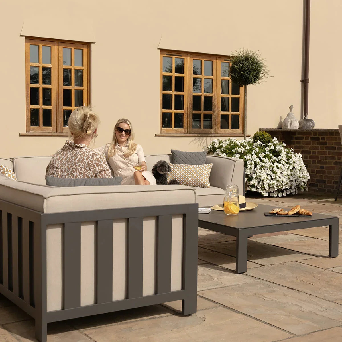 Grey outdoor sofa set with cream cushions and coffee table on stone patio