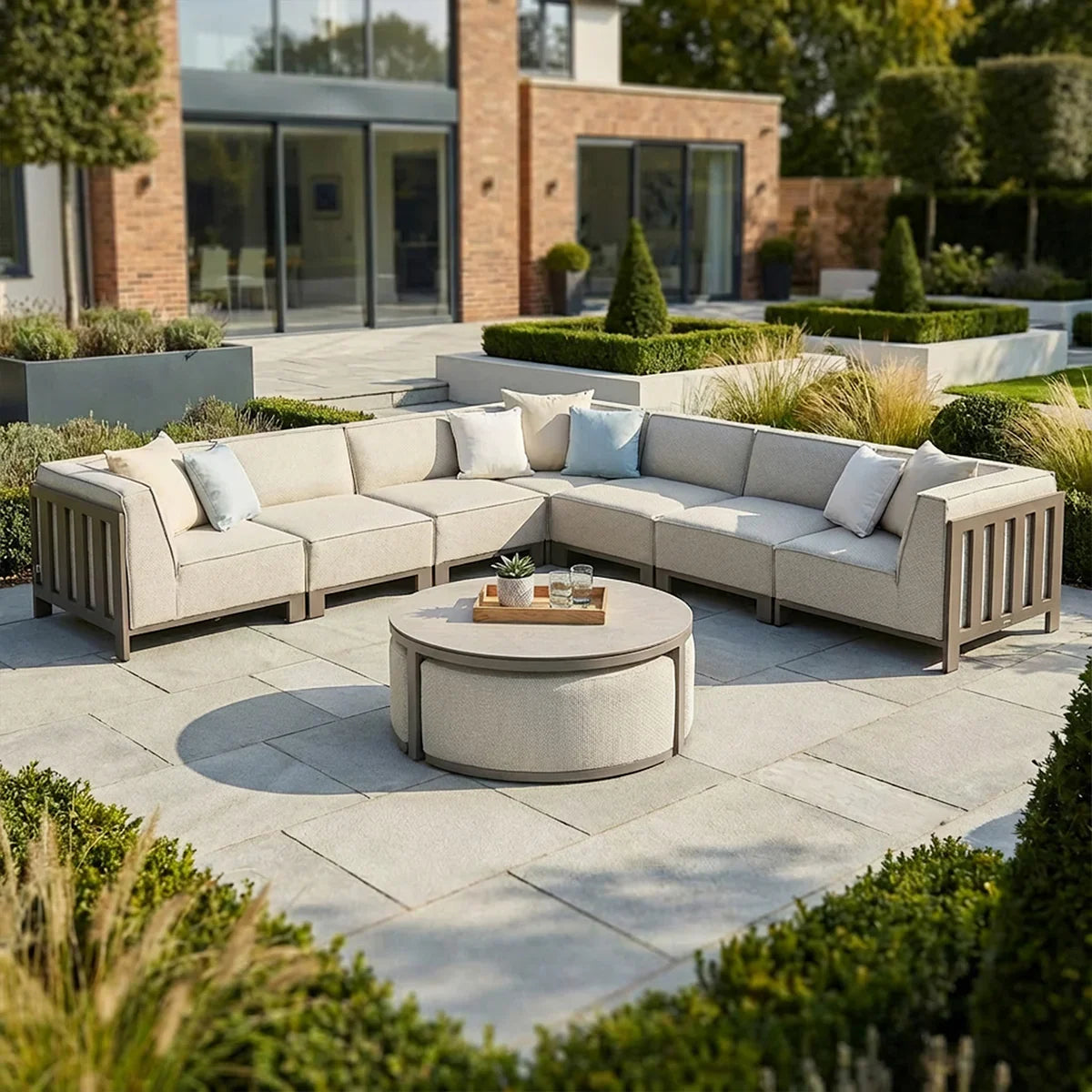 Beige outdoor corner sofa set with round coffee table on stone patio, modern garden setting