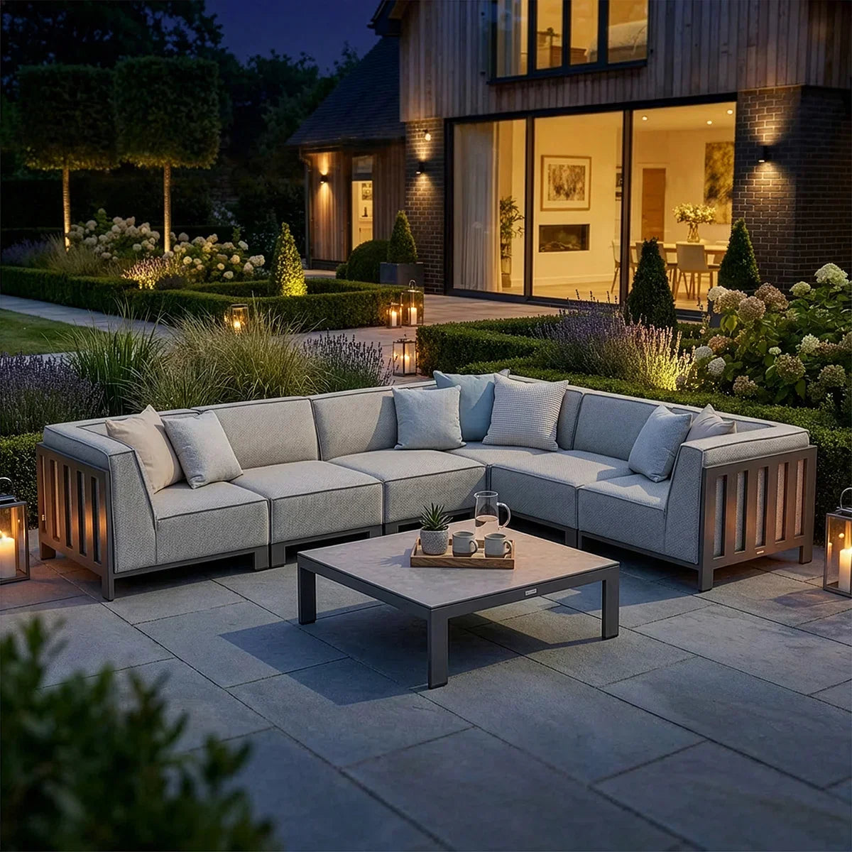 Grey outdoor corner sofa set with cushions and coffee table on a modern patio at dusk