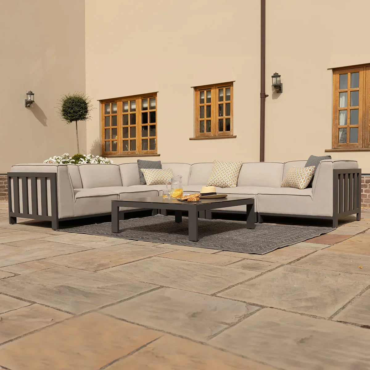 Grey outdoor corner sofa set with cushions and coffee table on patio