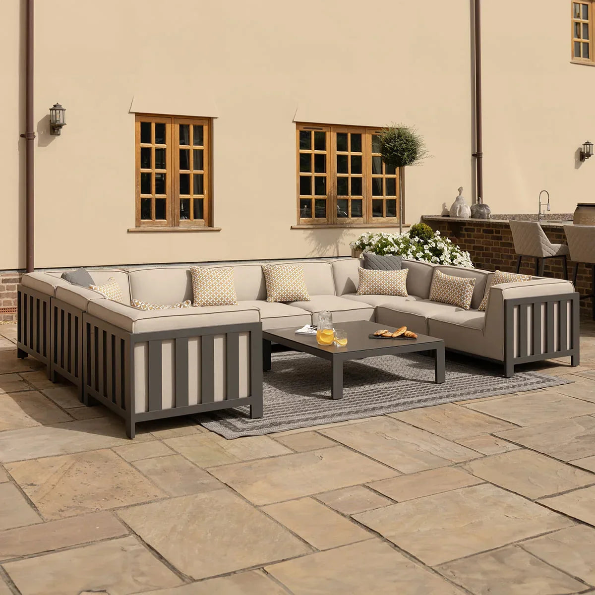 Outdoor corner sofa set with grey cushions, coffee table, and patterned pillows on patio