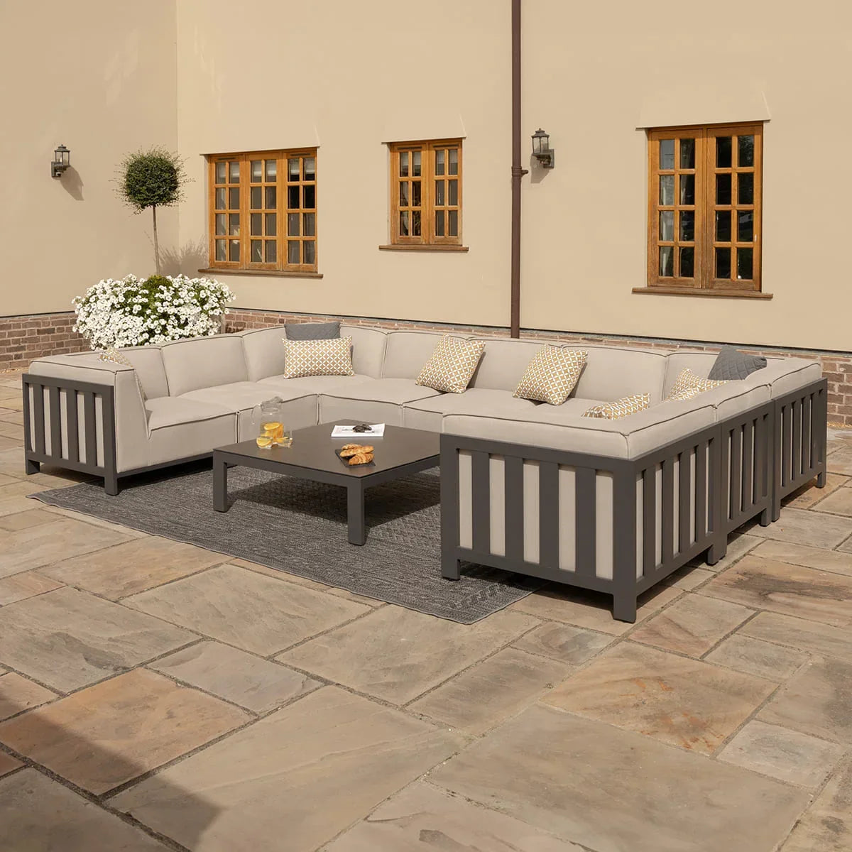 Grey outdoor corner sofa set with beige cushions and coffee table on patio