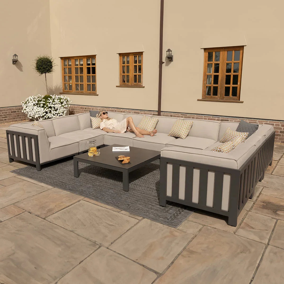 Grey outdoor corner sofa set with cushions and coffee table on patio