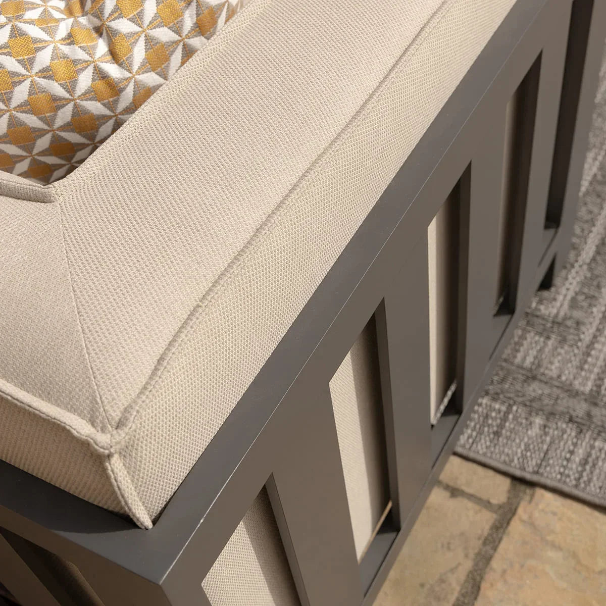 Closeup of outdoor sofa with beige cushion and grey frame on patio