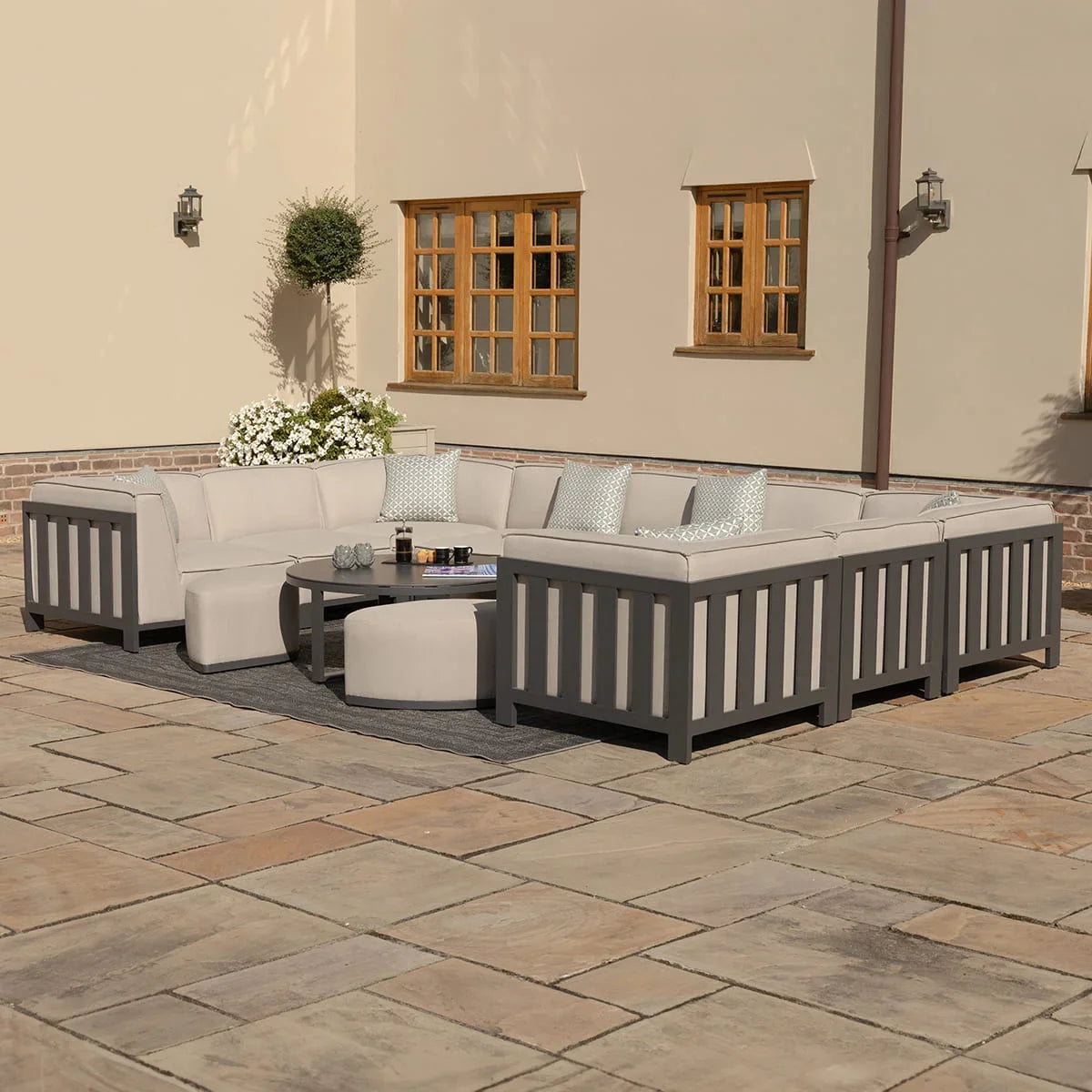 Grey outdoor corner sofa set with cushions and coffee table on stone patio