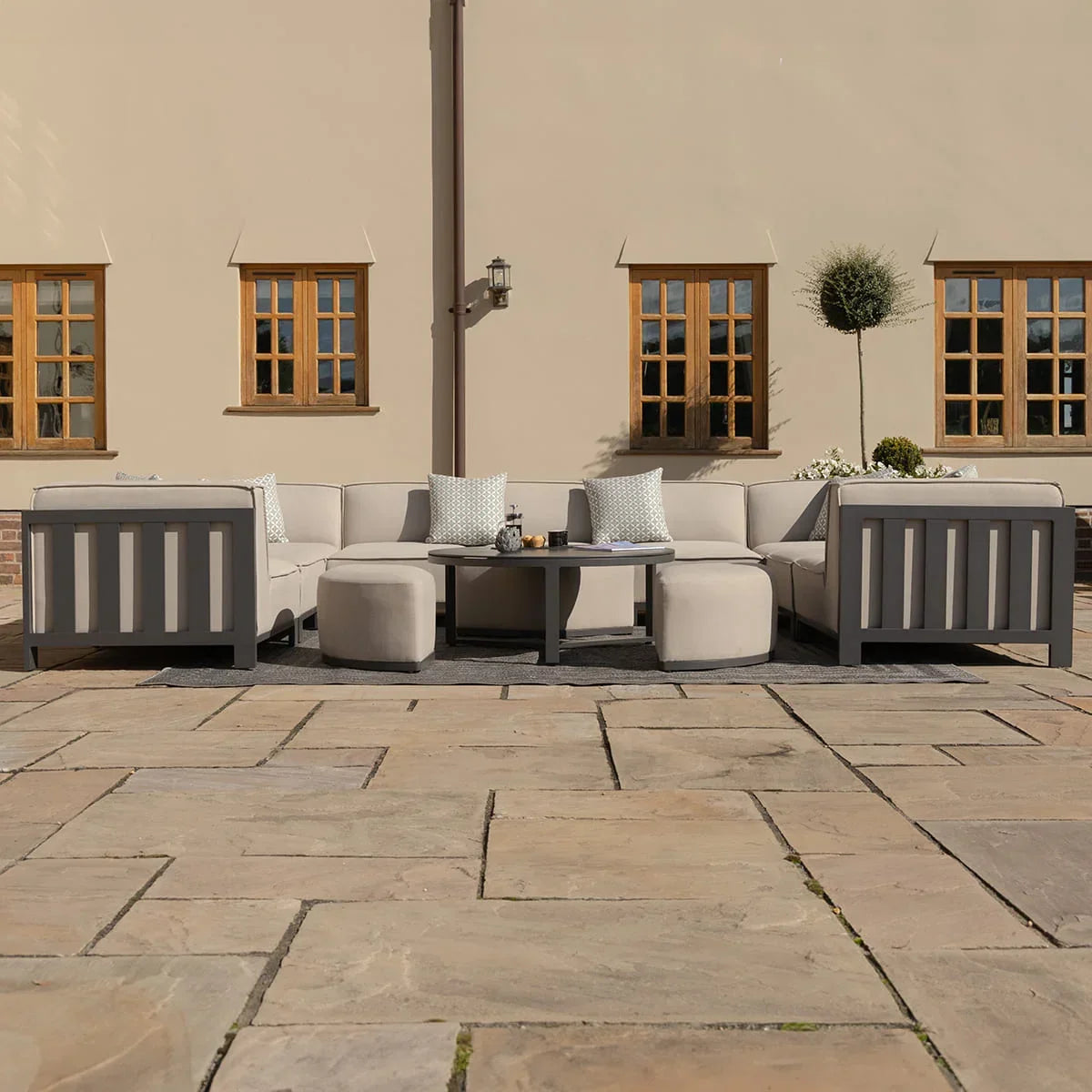 Outdoor corner sofa set with beige cushions and grey frame on stone patio