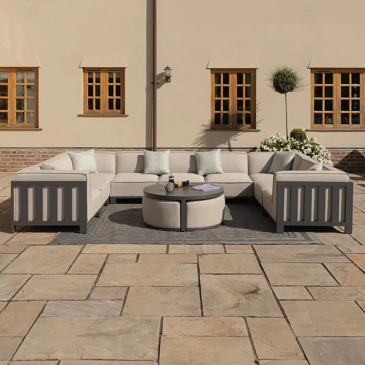 Beige outdoor corner sofa set with round coffee table on stone patio