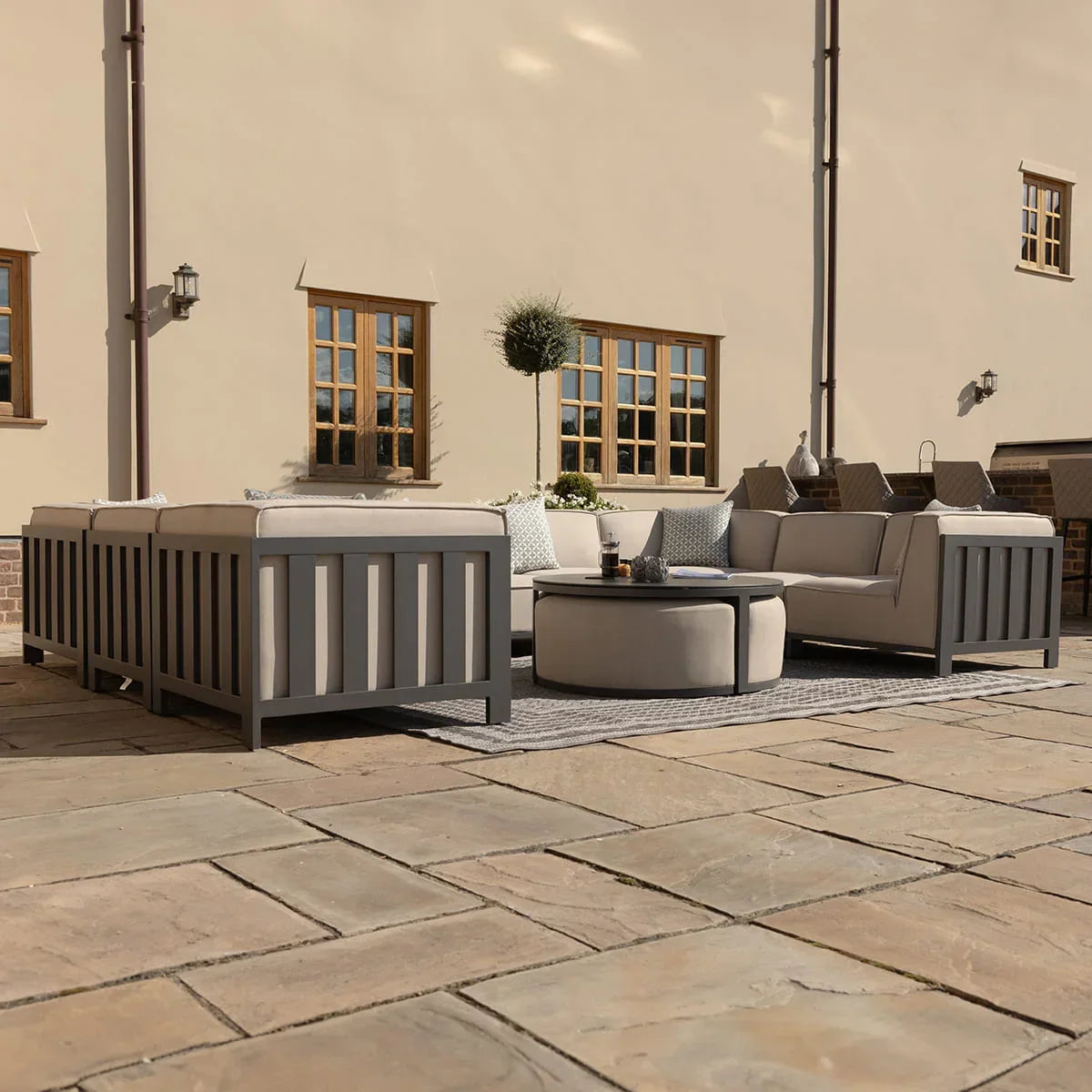 Grey outdoor sofa set with cushions and round coffee table on stone patio