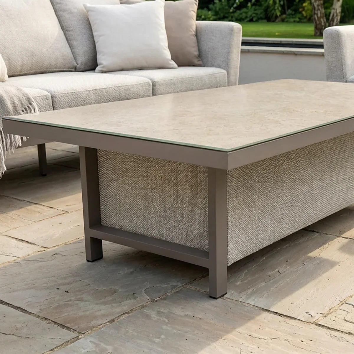 Outdoor coffee table with stone top and grey metal frame on patio beside fabric sofa