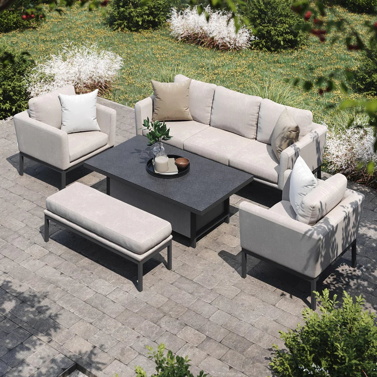 Beige outdoor sofa set with armchairs, bench and dark rectangular table on stone patio