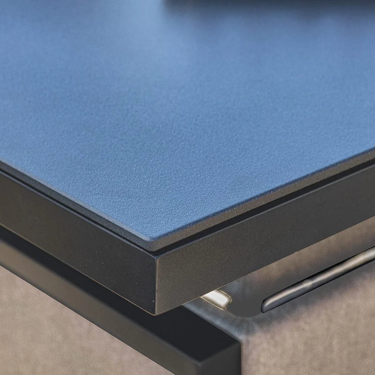 Close up of outdoor furniture table with textured black metal edge and glass top