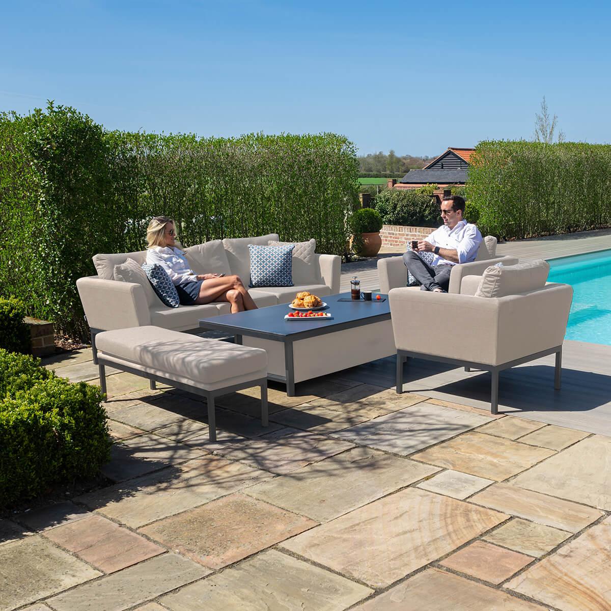 Beige garden sofa set with cushions and coffee table on patio beside a swimming pool