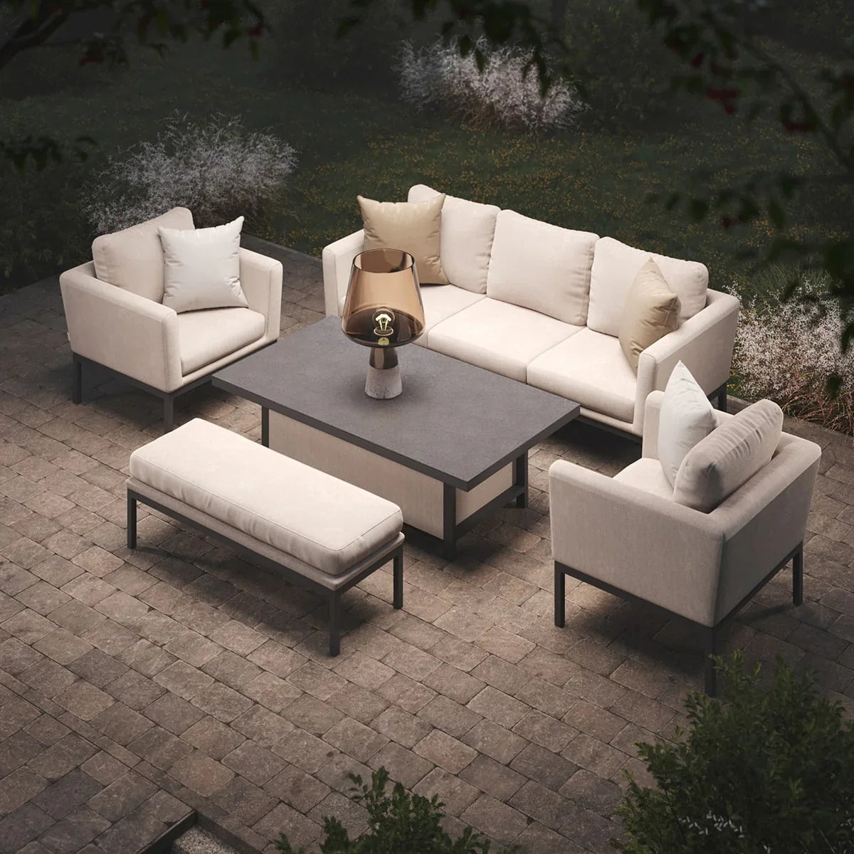 Cream outdoor sofa set with armchairs, bench, and grey table on stone patio
